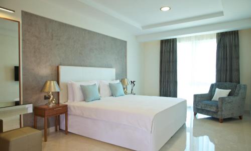 sypialnia z dużym białym łóżkiem i krzesłem w obiekcie Millennium Executive Apartments Muscat w Maskacie