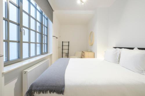 ein weißes Schlafzimmer mit einem großen Bett und Fenstern in der Unterkunft Appartement design 3 chambres proximité Grand-Place Bruxelles in Brüssel