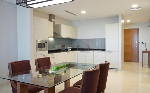 a kitchen with a table, chairs and a refrigerator at Millennium Executive Apartments Muscat in Muscat