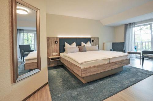 a bedroom with a large bed and a mirror at Hotel Grasberger Hof GmbH in Grasberg