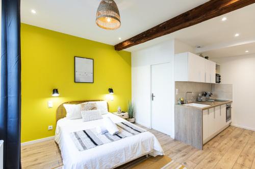 une chambre avec un mur jaune et un lit et une cuisine dans l'établissement La Belle de Nuit - Hôtel de Ville, à Saint-Étienne