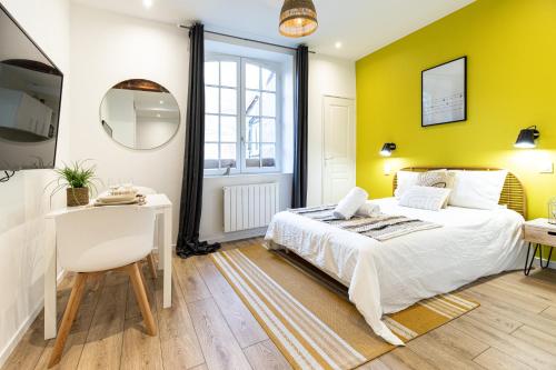 - une chambre avec des murs jaunes, un lit et un bureau dans l'établissement La Belle de Nuit - Hôtel de Ville, à Saint-Étienne