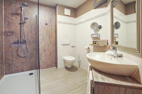 a bathroom with a shower and a sink and a toilet at Hotel Grasberger Hof GmbH in Grasberg