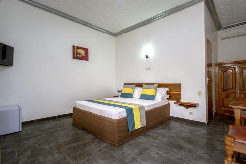 1 dormitorio con 1 cama grande con almohadas amarillas y azules en Hôtel le Relais de Kolda, en Kolda