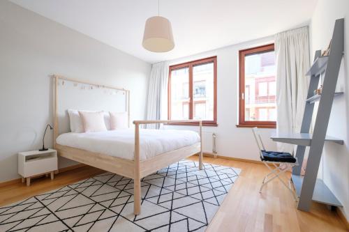 1 dormitorio con 1 cama y 2 ventanas en Chaleureux appartement 1 chambre proche Ecole Européenne, en Bruselas