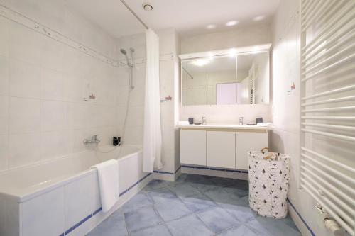 Baño blanco con bañera y lavamanos en Chaleureux appartement 1 chambre proche Ecole Européenne, en Bruselas