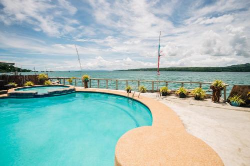 a swimming pool next to a body of water at La Casa de Samonteza in Camotes Islands