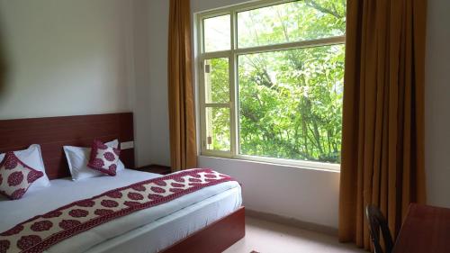 a bedroom with a bed and a large window at Harela Inn in Chamoli