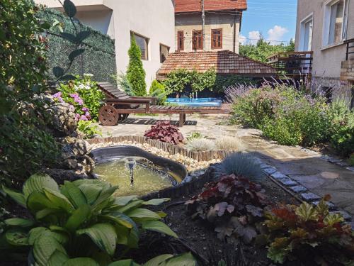 un jardín con un estanque frente a una casa en Mira Guest House en Dobrinishte