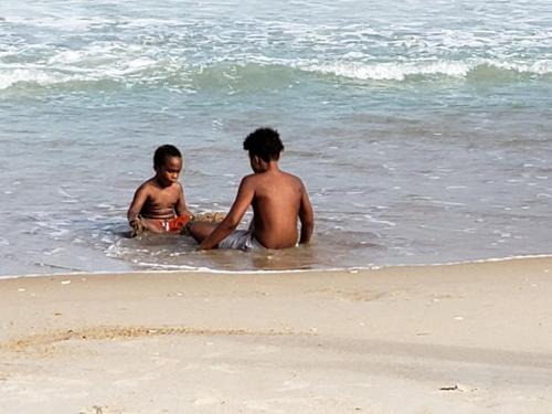 Due ragazzi seduti in acqua sulla spiaggia di 4 Sea Monkeys Apt. #3 a Surf City