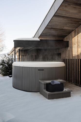 a hot tub in the snow next to a house at GOING TRIPLE A apartments EAST in Going