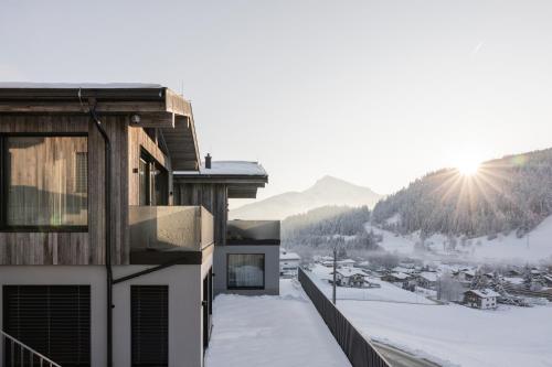 a building with the sun shining on the snow at GOING TRIPLE A apartments EAST in Going