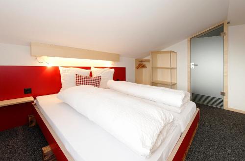 a bedroom with a large white bed with a red wall at Alpinhotel Bort in Grindelwald