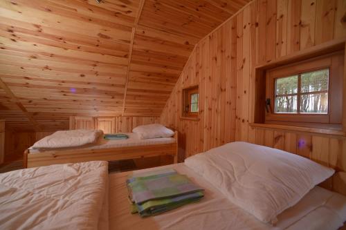 a bedroom with two beds in a wooden cabin at Domki przy plaży - Pod Wydmami in Dźwirzyno