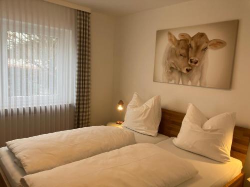 1 dormitorio con 2 camas y una foto de una vaca en Alpenflair Ferienwohnungen Schulz, en Oberstdorf