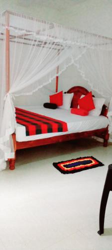 a bedroom with a bed with red and black pillows at Pradeep Guest House in Mirissa