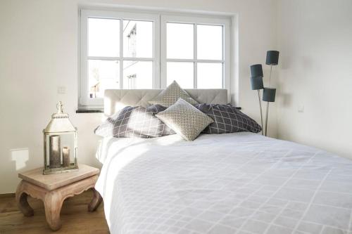 una camera da letto con un letto bianco con cuscini e un tavolo di Loft “Samuel” a Utting am Ammersee
