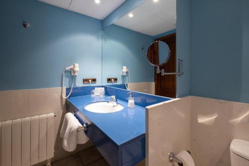 a blue bathroom with a sink and a mirror at Hotel Calitxo in Molló