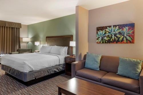 Holiday Inn Express & Suites Indio - Coachella Valley, an IHG Hotel في إنديو: غرفه فندقيه بسرير واريكه