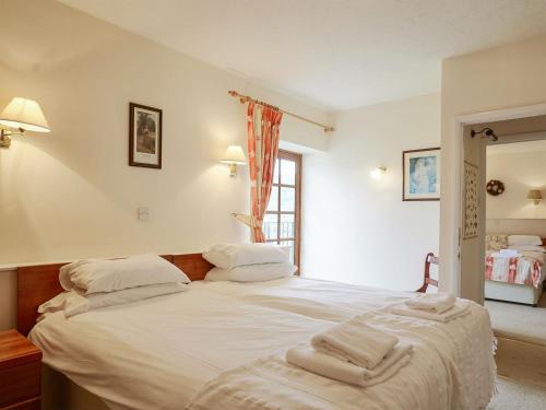 una camera da letto con un grande letto bianco con asciugamani di The Carriages a Sidbury