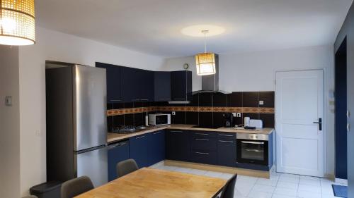 een keuken met blauwe kasten en een houten tafel bij Le Mont comme à la maison in Roz-sur-Couesnon