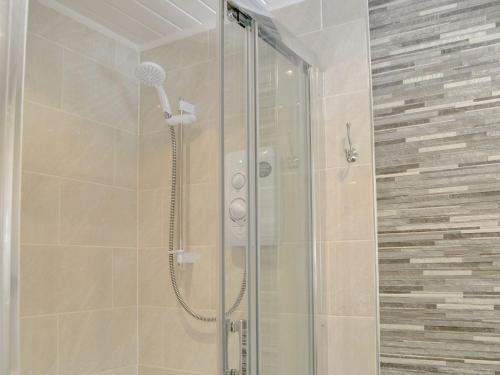 a shower with a glass door in a bathroom at Maple Lodge in Otterburn