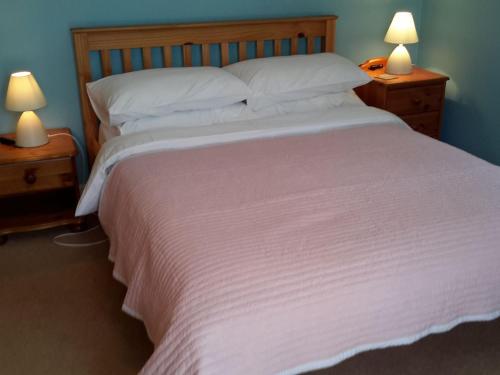 um quarto com uma grande cama branca e 2 candeeiros em Sunshine Cottage em Fairford