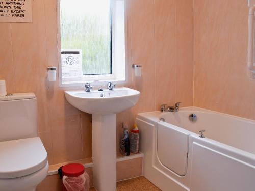 a bathroom with a sink and a toilet and a bath tub at Sunshine Cottage in Fairford