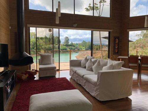 una sala de estar con muebles blancos y ventanas grandes. en Guatapulco, en Guatapé