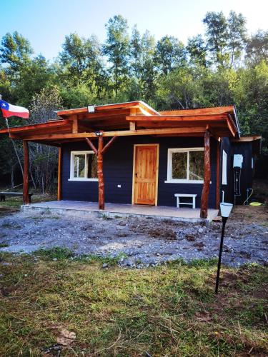 una pequeña casa azul con porche y puerta en Cabañas Orillas Del Nilahue, en Riñinahue