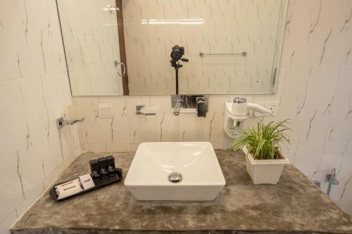 a bathroom with a white sink and a mirror at Sigiriya Wewa Addara Hotel - Hotel By The Lake in Sigiriya