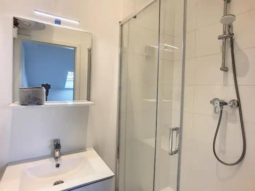 La salle de bains est pourvue d'une douche en verre et d'un lavabo. dans l'établissement Appartement 021, à Liège