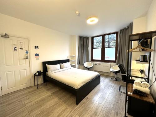 Schlafzimmer mit einem Bett, einem Schreibtisch und einem Fenster in der Unterkunft Sleeplicity London Heathrow in Feltham