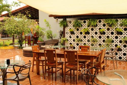 アンシエタにあるPousada No Meio do Mundoの壁に植物を植えたテーブルと椅子のあるレストラン