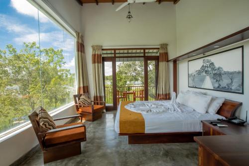 a bedroom with a bed and a large window at Sigiriya Wewa Addara Hotel - Hotel By The Lake in Sigiriya