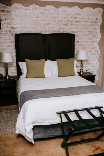 a large bed with a black headboard and two lamps at La Bendicion in eMalahleni