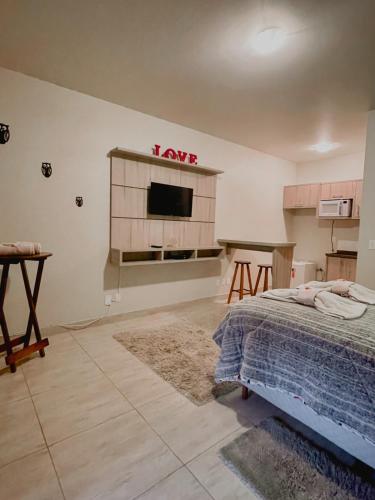 a bedroom with a bed and a tv on the wall at Apartamento Girassol love in Monte Verde