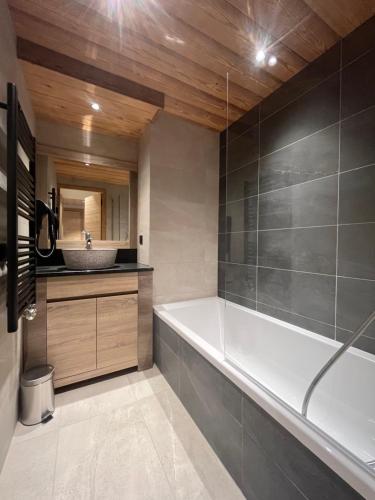 une salle de bain avec une baignoire et un lavabo dans l'établissement Chalet Emeraude - 10 personnes - Plagne Soleil, à Plagne Villages