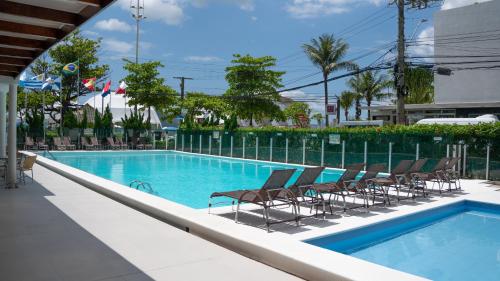 a swimming pool with chairs and a fence at Marambaia Hotel e Convenções in Balneário Camboriú