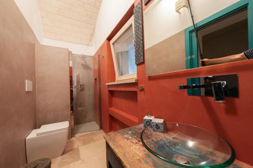 uma casa de banho com um lavatório de vidro e um WC. em TRULLI ACQUASALA - Apulian Country Experience em Ostuni