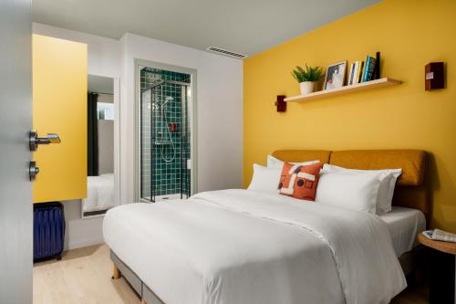 a bedroom with a white bed and yellow walls at Edgar Suites Vicat - Porte de Versailles in Paris