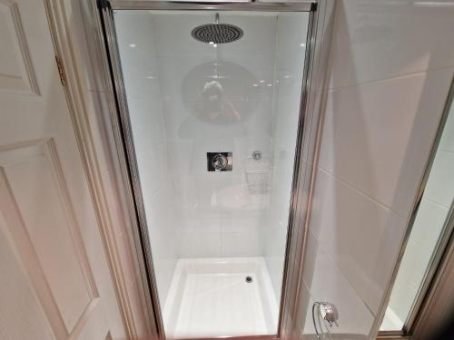 La salle de bains est pourvue d'une douche avec une porte en verre. dans l'établissement Landing Cottage Guest House, à Newby Bridge