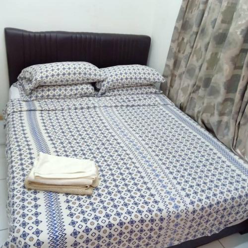 ein Bett mit einer blauen und weißen Bettdecke und Kissen in der Unterkunft jm in Shah Alam