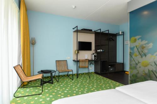 a room with a bed and a table and chairs at Hotel De Roode Schuur in Nijkerk