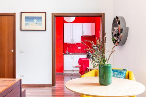 a living room with a table and a red kitchen at Easylife - Accogliente monolocale in zona Ripamonti in Milan