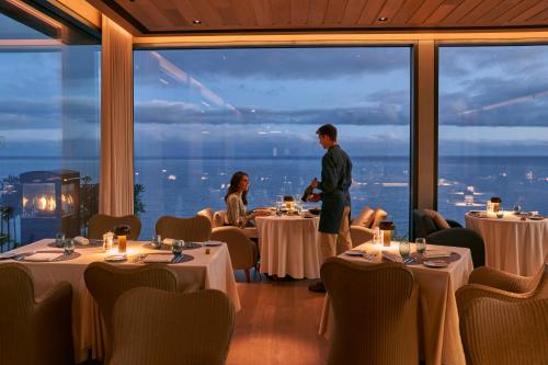 un uomo e una donna in piedi in un ristorante con tavoli di Les Suites at The Cliff Bay - PortoBay a Funchal