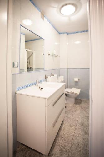 a white bathroom with a sink and a toilet at Vega La Escuela megustarural in Llanes