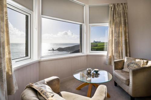 a living room with two chairs and a table and two windows at Housel Bay Hotel in Lizard