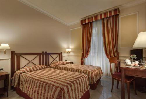 a hotel room with two beds and a desk at Palazzo Cardinal Cesi in Rome