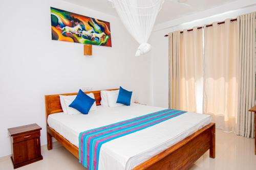 a bedroom with a large bed with blue pillows at Nico Beach Hotel in Hikkaduwa